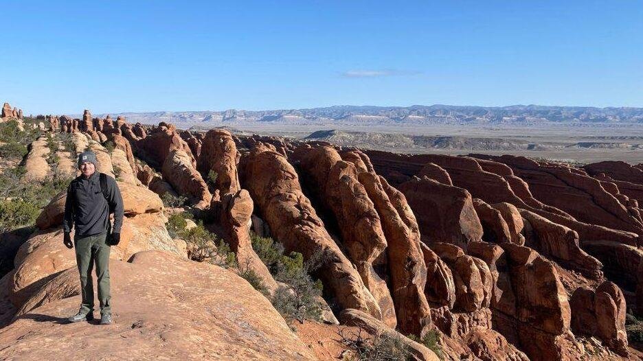 A man standing by the rock fins on devils garden hike