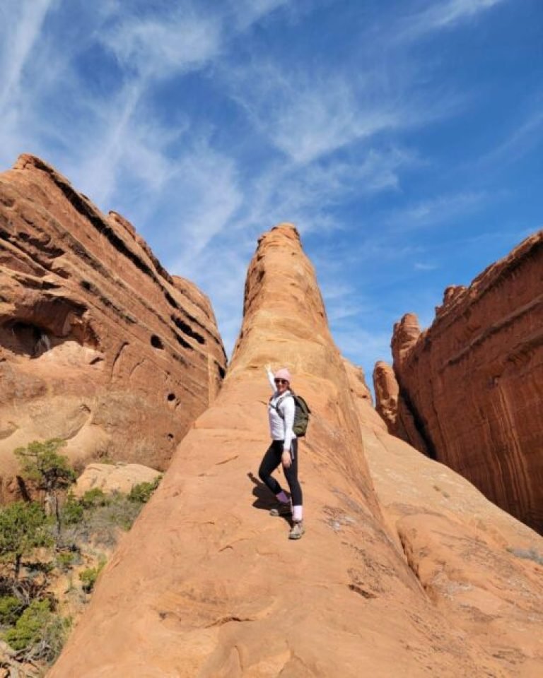 A woman mimicking skiing down a rock fin on devils garden hike